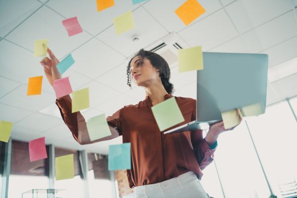 Woman looking through her sticky notes while using her laptop